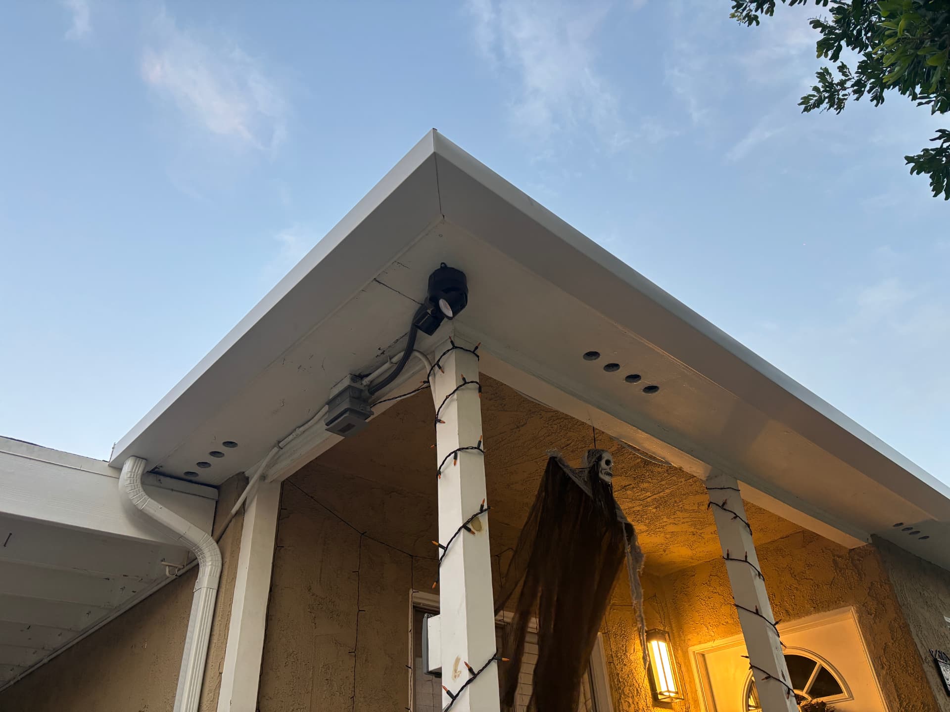 White gutter and downspout installed at a porch corner