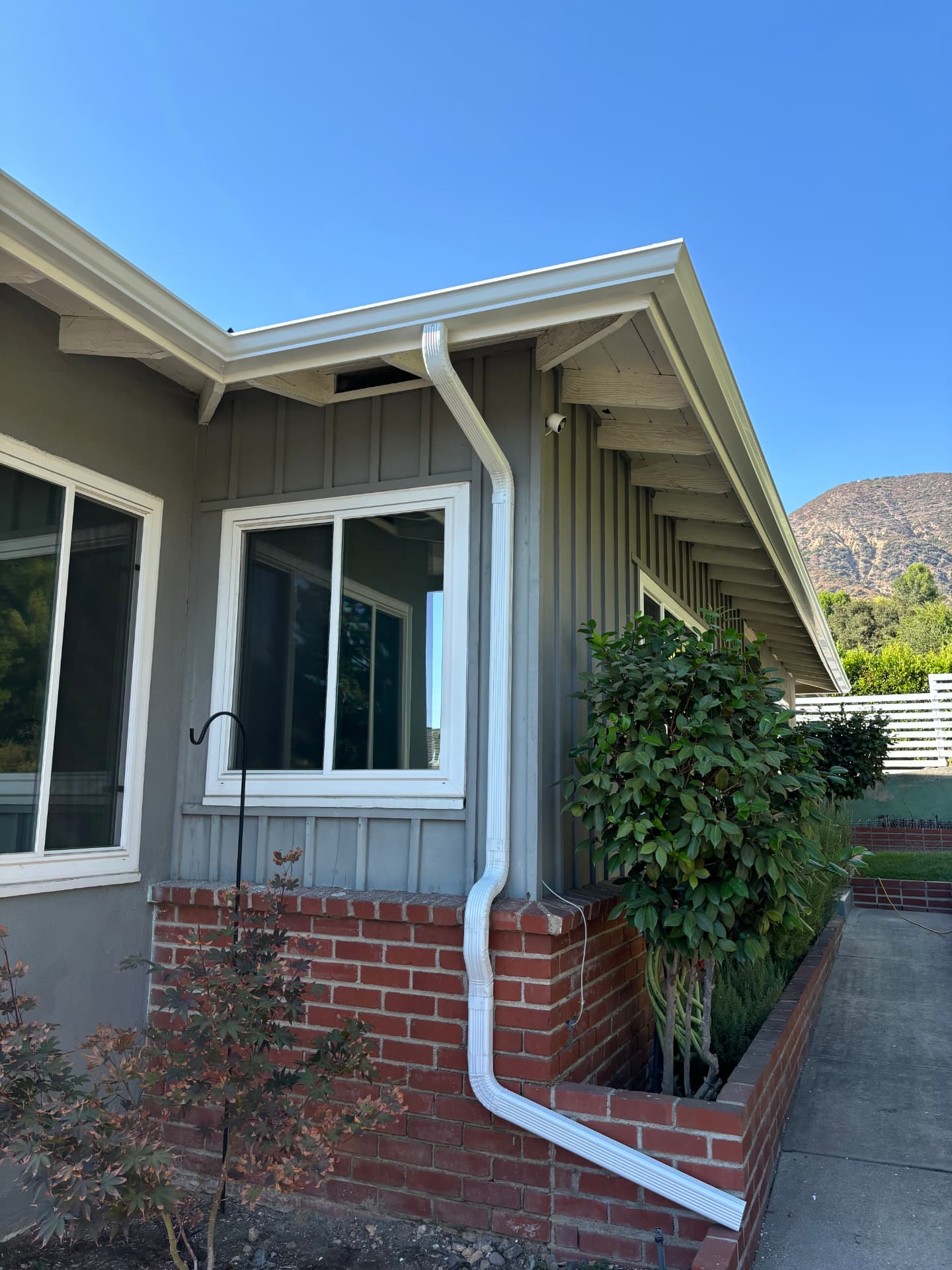 White downspout routed along brick on a Southern California home