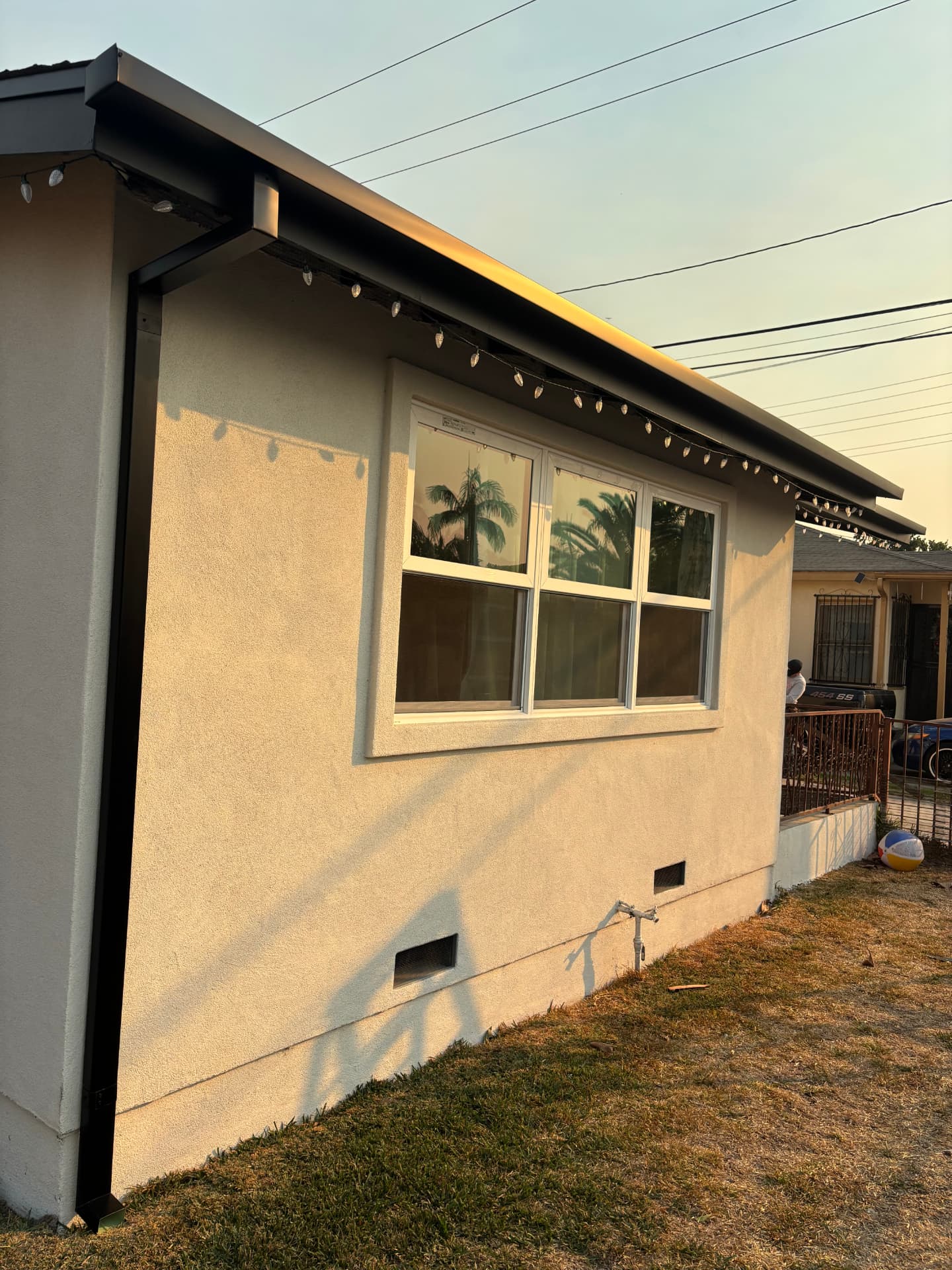 Black seamless gutter installed along a stucco home